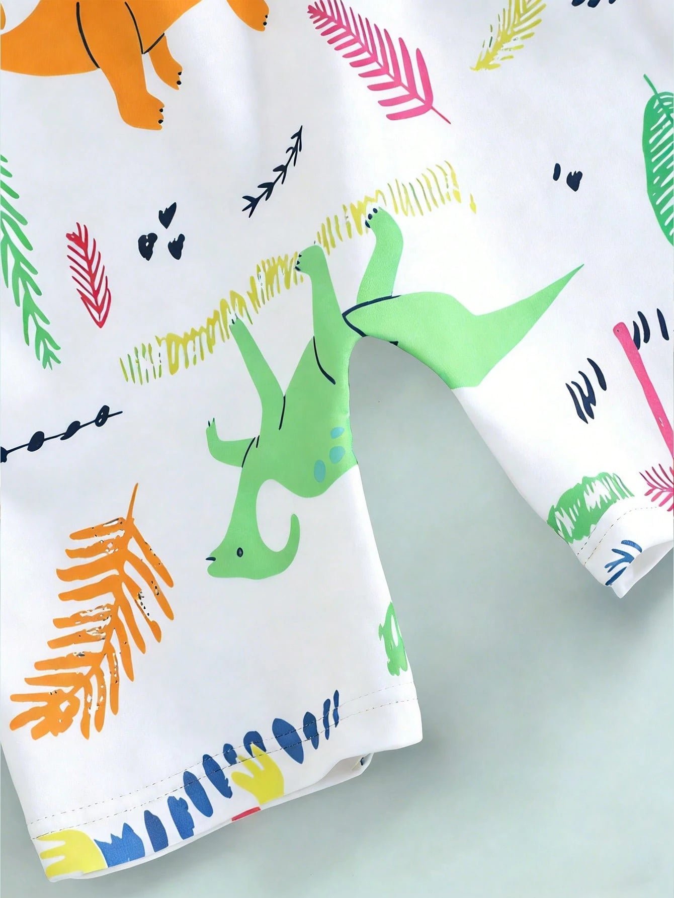 Prenda blanca traje de baño para bebe con estampado tropical de dinosaurios detalle lateral