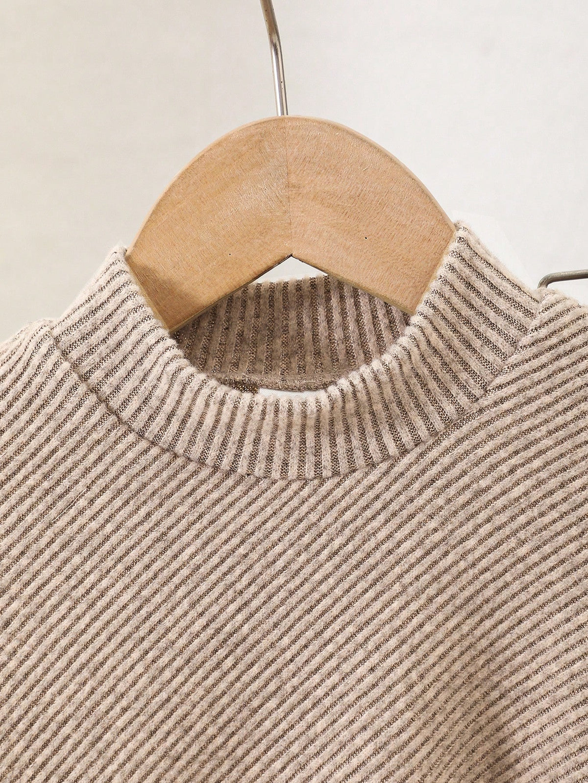 Suéter caqui de punto acanalado para bebé, detalle del cuello alzado y textura del tejido.