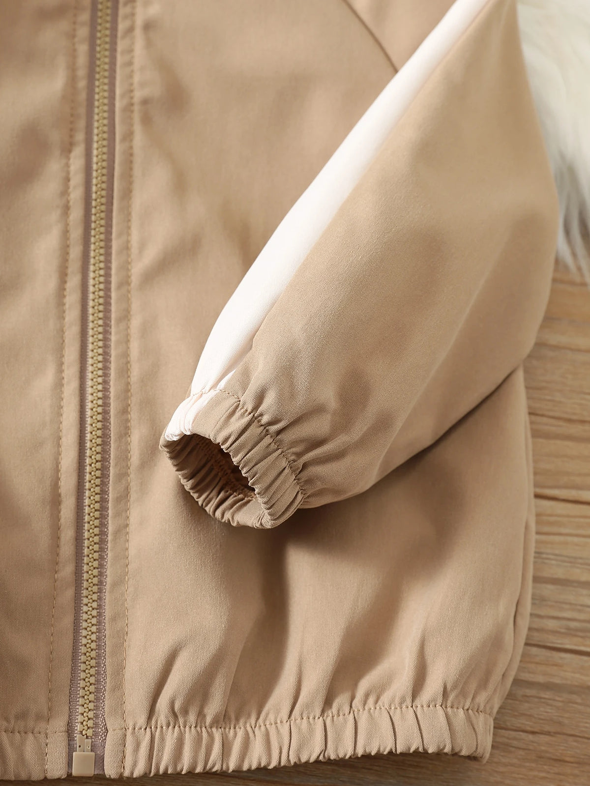 Prenda beige chaqueta deportiva para bebe con cuello alto y cremallera