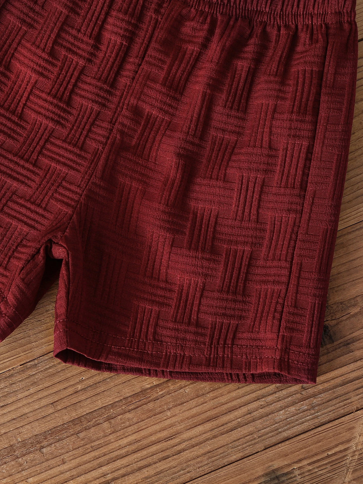 Pantalón corto burdeos para bebé con textura jacquard y detalle del acabado.