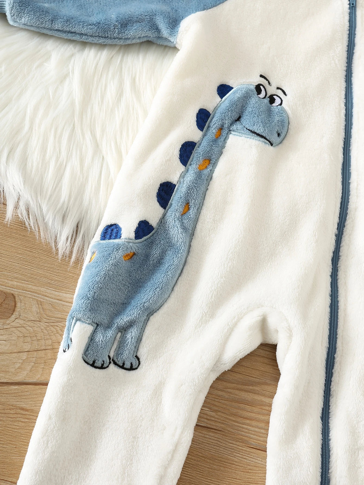 Prenda azul y blanca mameluco para bebe con detalle de dinosaurio en relieve
