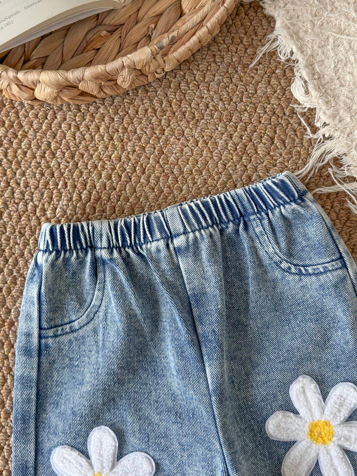 Pantalón de mezclilla azul para bebe con flores aplicadas y detalle de cintura elástica