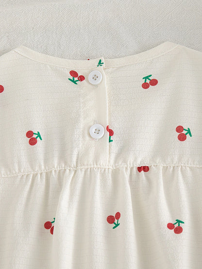 Blusa beige para bebe con cerezas y detalle de botones blancos posteriores