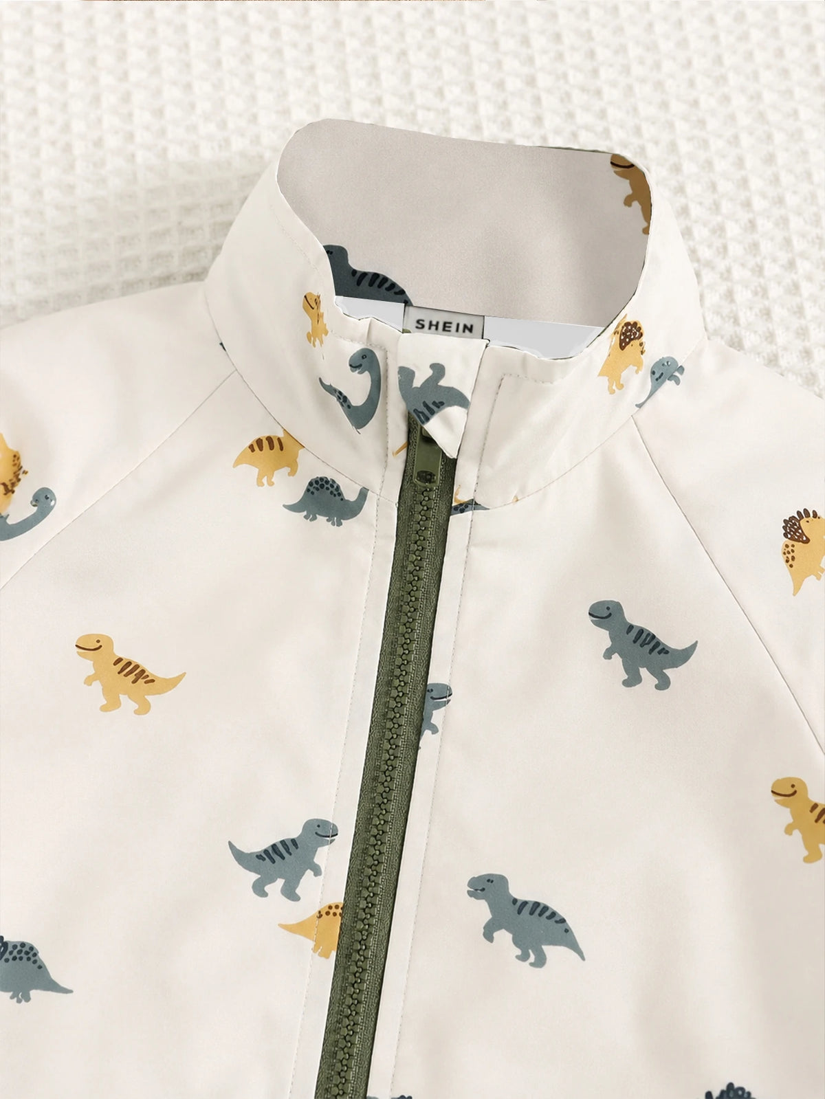Chaqueta crema para bebe con detalle de cuello alto y cremallera verde oliva