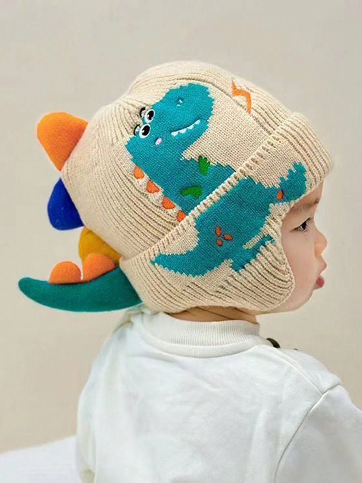 Prenda beige gorro para bebe con dinosaurio tejido usado en bebé vista lateral