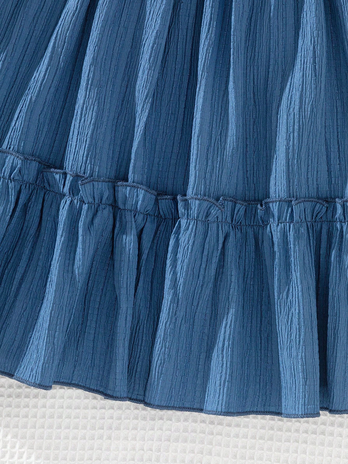 Prenda azul vestido para bebe con detalle de textura y acabado de falda
