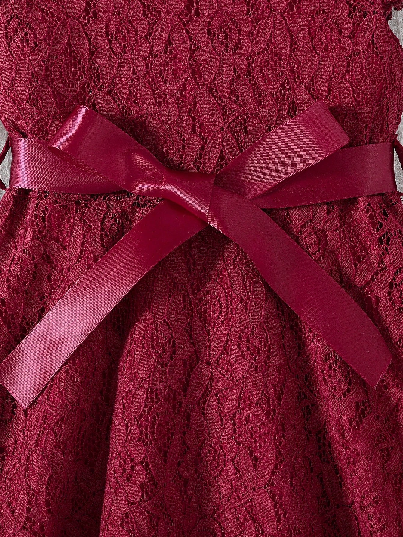 Prenda burdeos vestido de encaje para bebe detalle de lazo y acabado floral