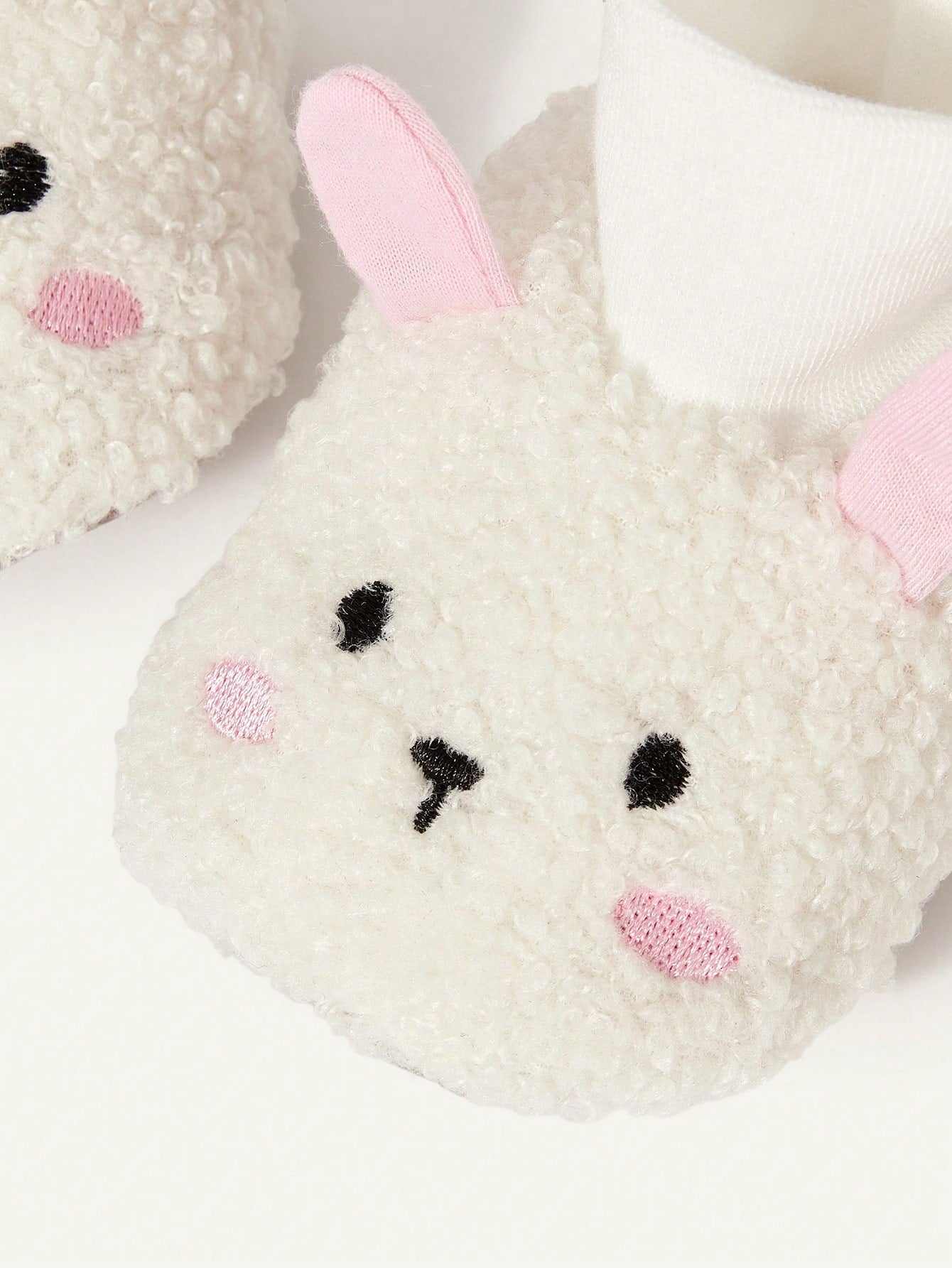 Prenda blanca pantuflas para bebe con orejas rosadas detalle lateral
