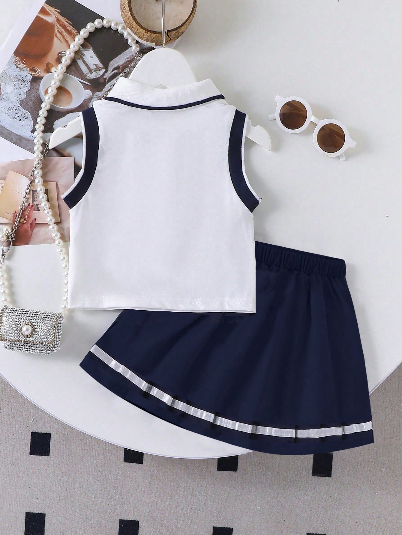 Prenda blanco y azul marino conjunto para bebe con camisa polo y falda plisada vista trasera