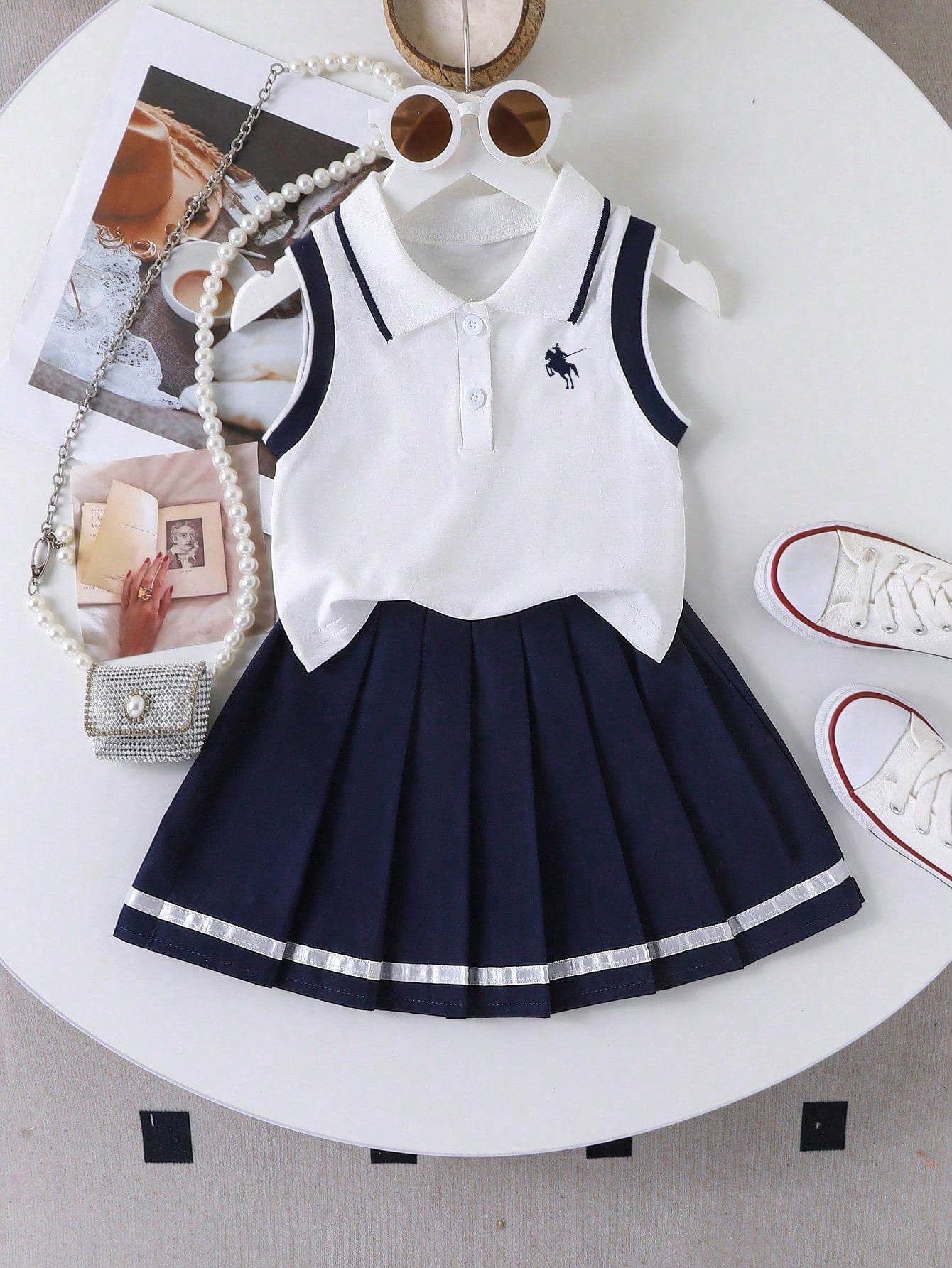 Prenda blanco y azul marino conjunto para bebe con camisa polo y falda plisada vista frontal