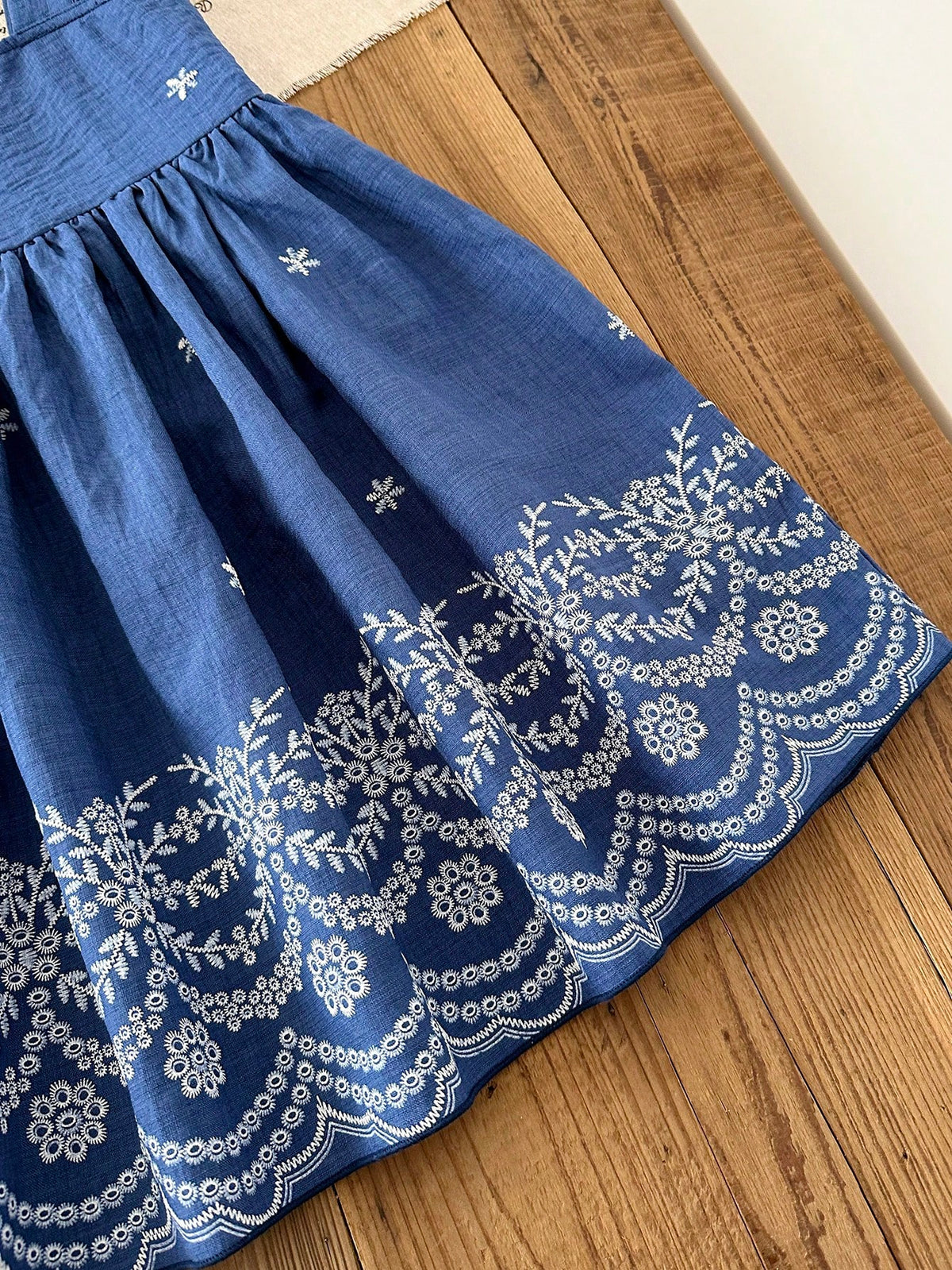 Prenda azul vestido para bebe detalle de acabado floral blanco en el bajo