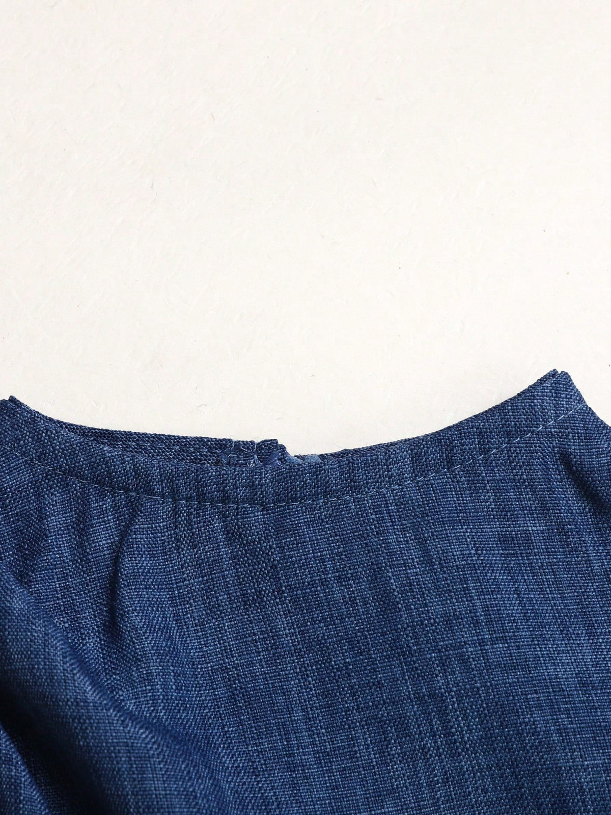 Prenda azul vestido para bebe detalle de cuello alzado y acabado de tela