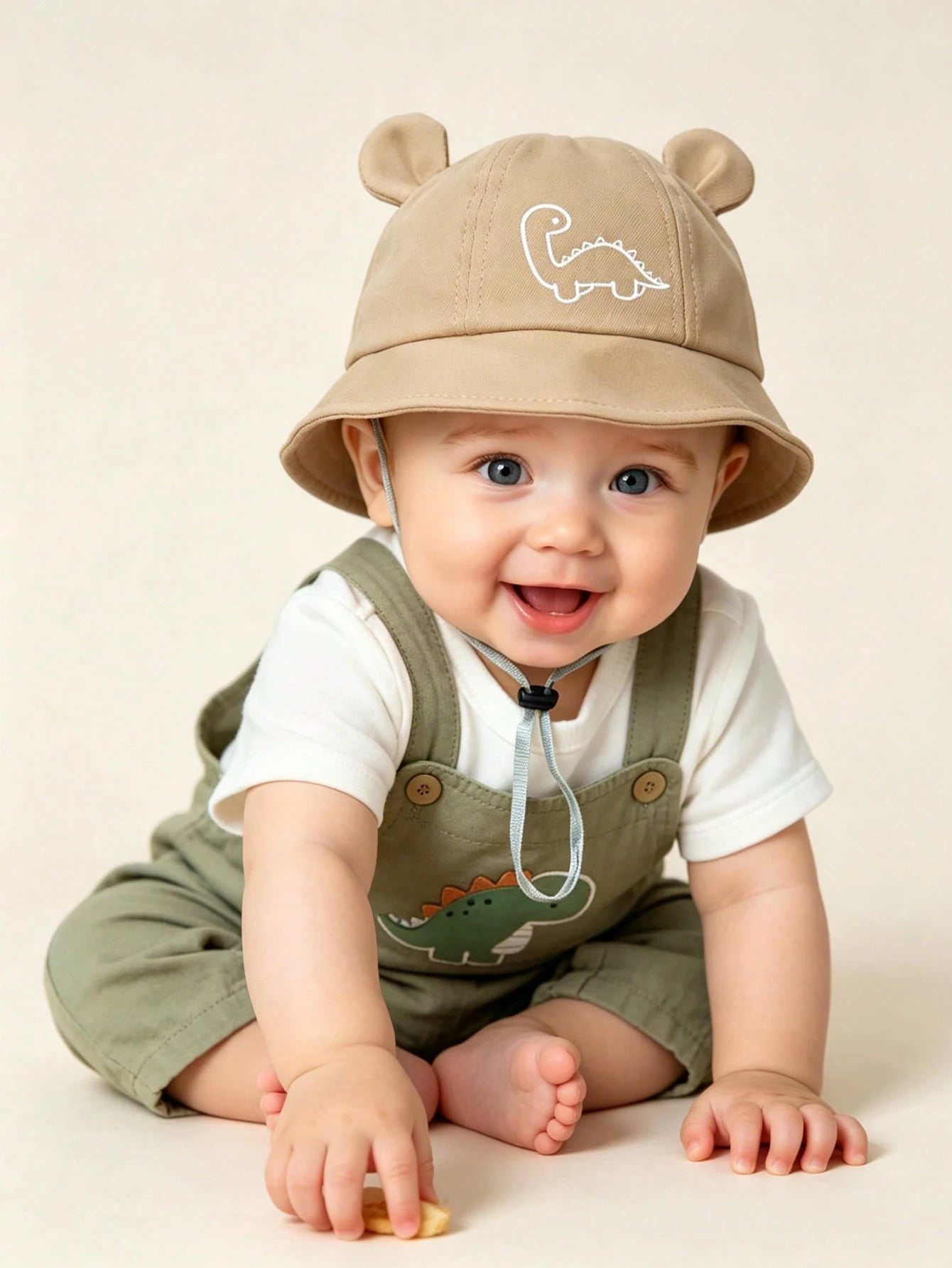 Prenda beige sombrero de cubo para bebe con orejitas y dinosaurio durante uso