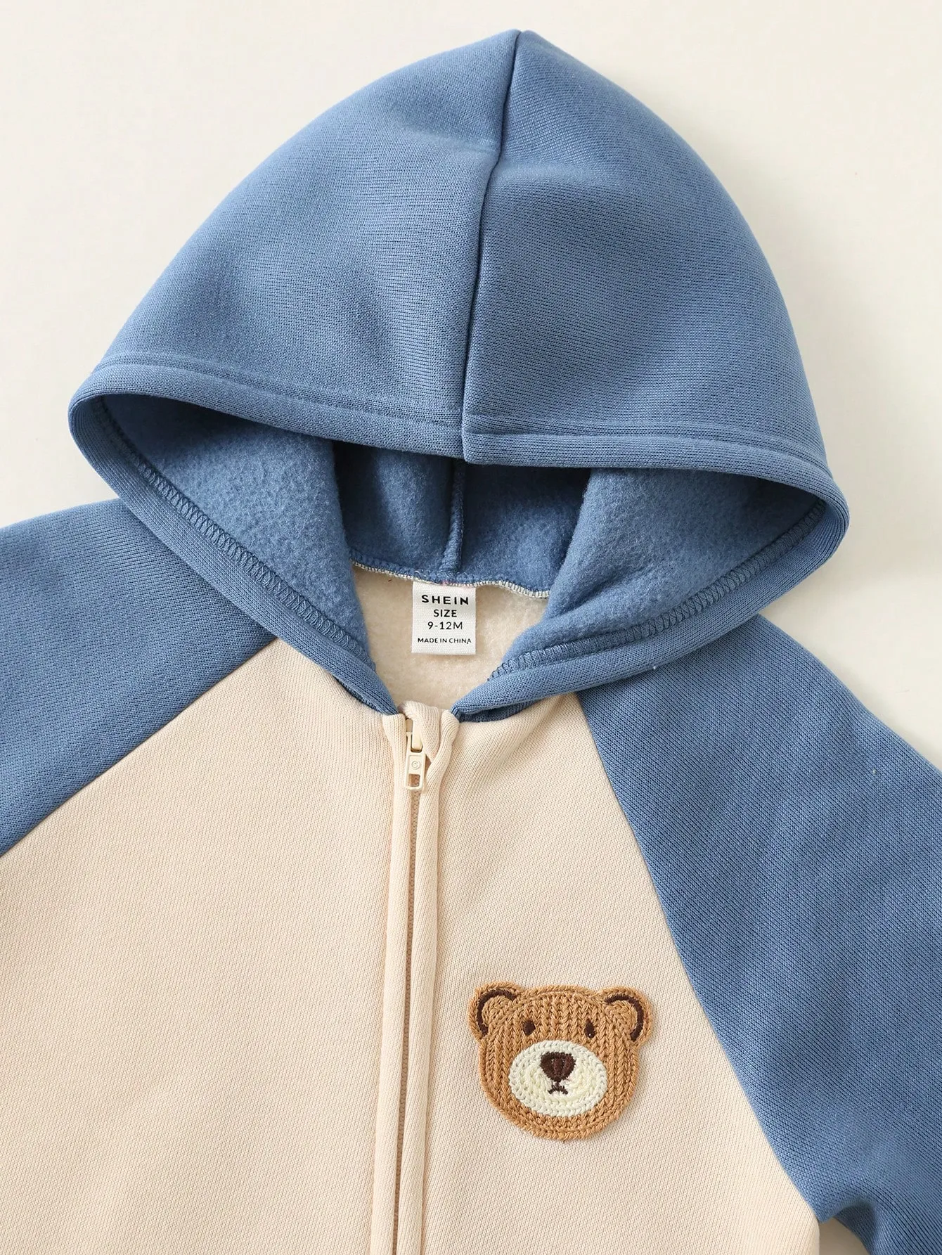 Mameluco beige azul con capucha y diseño de oso bordado